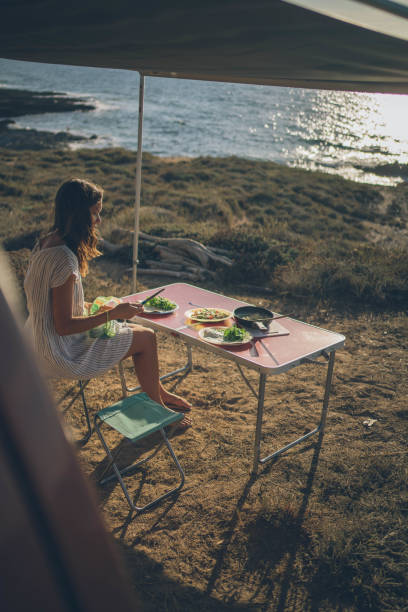 istock Young woman eats breakfast on a picnic table by the sea 1352700470