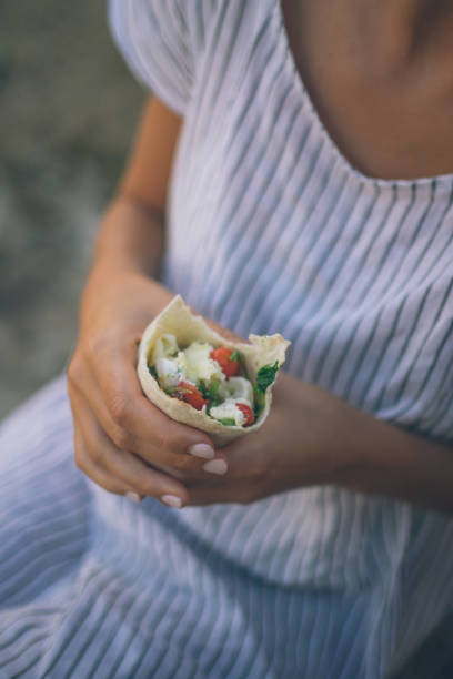 istock Young woman eats fresh vegetable wrap with cheese 1352700487