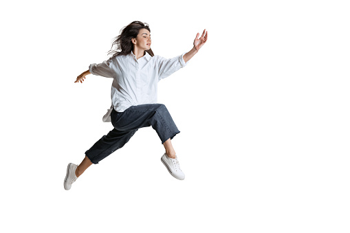 Passing. Young woman in casual wear moving dynamically isolated on white background. Flexible female ballet, contemporary dancer weightless moves. Art, motion, action, flexibility, inspiration concept