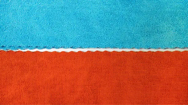 Edge texture of blue and red microfiber fabric. Selective focus. White background.