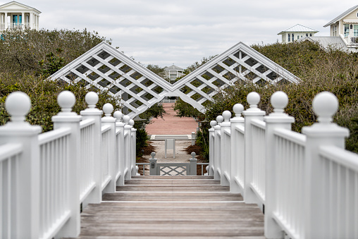 Pavilion wooden steps and railing in classic white new urbanism architecture style boardwalk by beach to Seaside, Florida town at Gulf of Mexico panhandle framing of gate