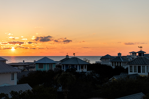 Aerial view on colorful yellow sunset sun with ocean landscape of Gulf of Mexico in Seaside, Florida from rooftop terrace buildings houses cityscape and weather vanes