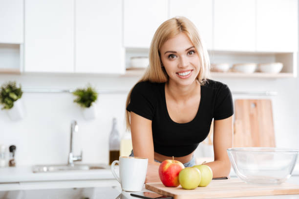 istock Woman leaning on a table while standing at the kitchen 1352707617