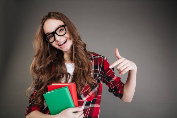 istock Pretty young woman holding books in hands while pointing. 1352709476