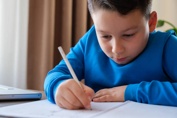 istock 8 years old cute child doing homework at home 1352710121