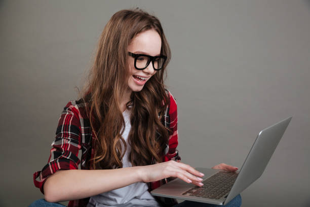 istock Pretty smiling young lady chatting by laptop computer 1352710262