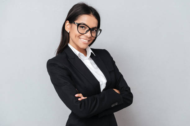 istock Smiling successful woman in suit standing with arms folded 1352711022