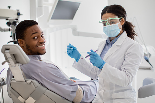 Limpieza dental profesional. Dentista negra que tiene tratamiento con paciente masculino photo