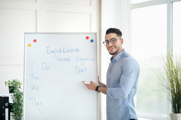 istock Happy male English standing near blackboard, explaining foreign language rules from home office 1352712321