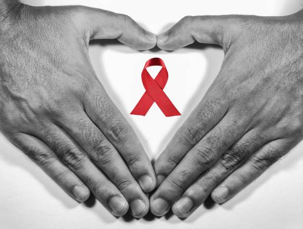 mann, der mit seinen händen und einem roten band ein herz für den kampf gegen aids auf weißem hintergrund bildet. - symbol sex healthcare and medicine healthy lifestyle stock-fotos und bilder