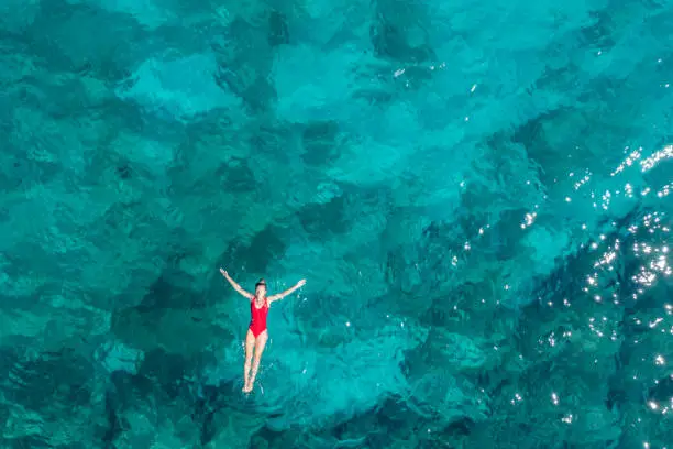 She wears a red swimsuit that contrastes the blue of the sea.
Croatia