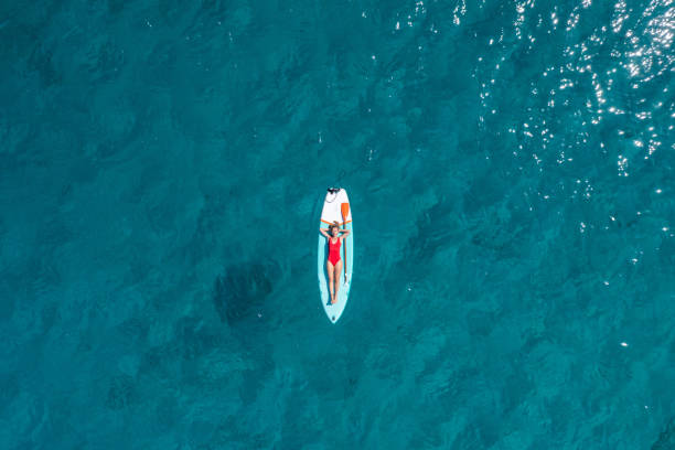 vue aérienne d’une femme flottant sur un stand up paddle - paddle surfing photos et images de collection