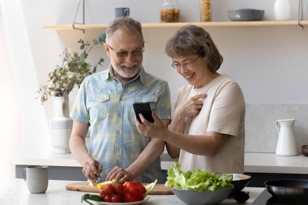 istock Happy old couple cooking, using cellphone applications. 1352716034