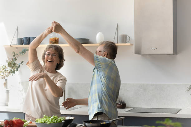 Happy older retired man dancing with elderly wife.