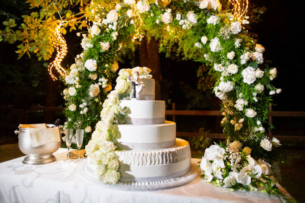 Large wedding cake arranged on a table set up in the garden in the evening with decorative flowers stock photo