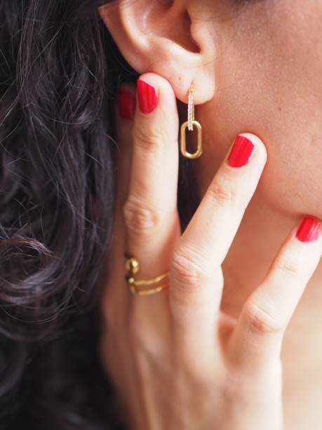 sicherheitsnadelring und ohrring an einer braunhaarigen frau - gold earrings stock-fotos und bilder