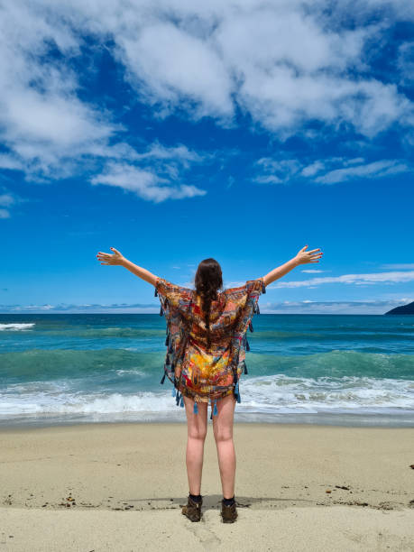 istock Young man with open arms looking at the horizon on deserted beach 1352717587