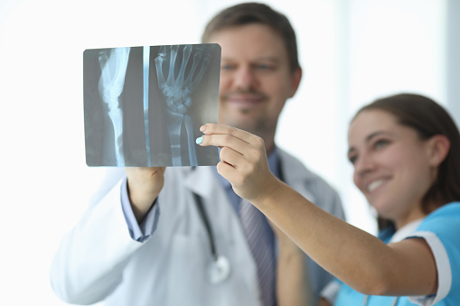 Doctors looking at xray of hand in clinic closeup. X ray diagnosis of arthritis concept