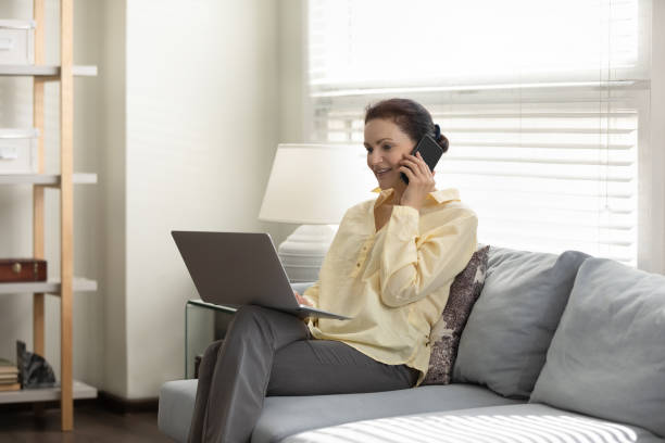 Smiling middle aged businesswoman multitasking at home office.