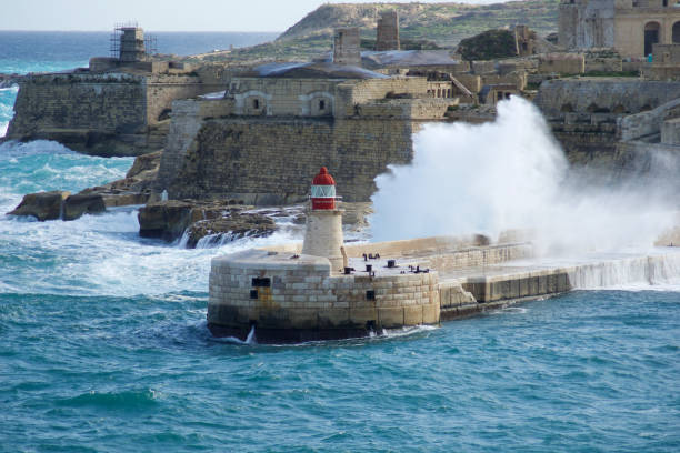 vista desde fort st elmo hasta el ricasoli grand harbour east breakwater y el faro rojo durante las fuertes olas - st elmo fotografías e imágenes de stock