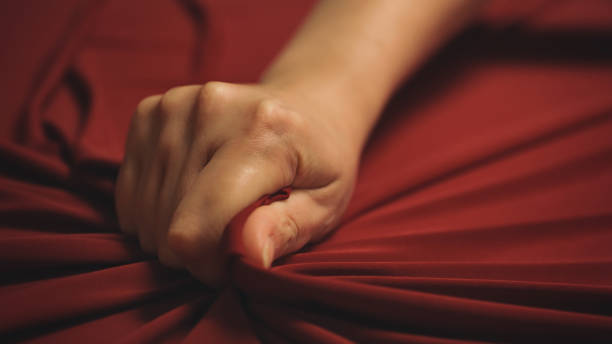 女性の手は情熱的に赤いベッドシーツを絞ります。ラブコンセプト。 - 性的行為 ストックフォトと画像