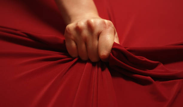 Woman hand passionately squeezes red bed sheet. Love concept. stock photo