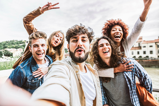 Multicultural happy friends having fun taking group selfie portrait on city street - Young diverse people celebrating laughing together outdoors - Happy lifestyle concept