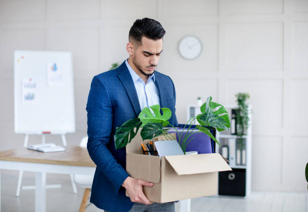 Unemployed Arab guy in formal wear holding personal belongings, feeling depressed after losing his job Unemployed Arab guy in formal wear holding personal belongings, feeling depressed after losing his job. Upset Eastern man with cardboard box of things leaving office after being fired fired employee stock pictures, royalty-free photos & images