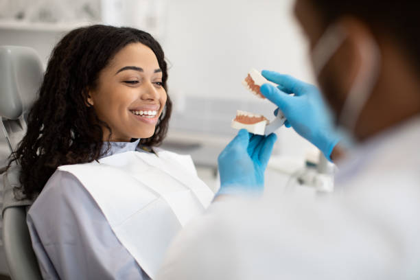 oral care. black stomatologist doctor demonstrating plastic jaw to female patient - dentist surgery dental hygiene using voice imagens e fotografias de stock