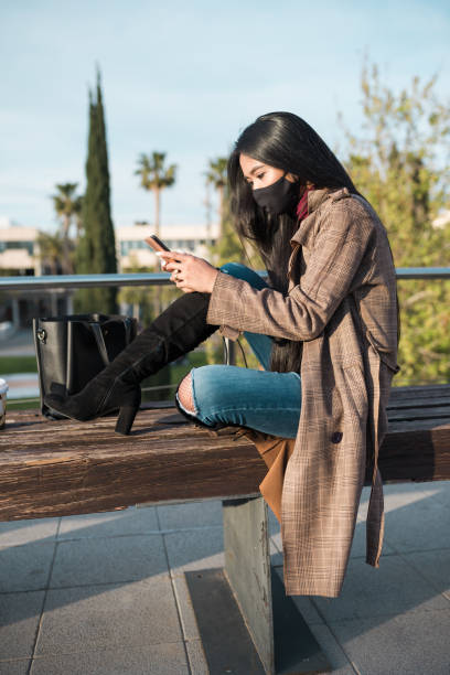istock Female in mask texting on smartphone 1352728651