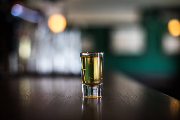 shot glass on a bar counter - shot glass glass alcohol color image imagens e fotografias de stock