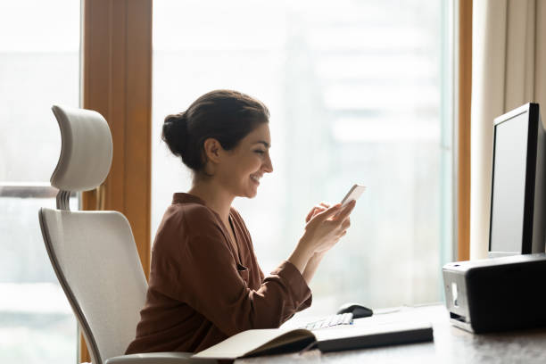 istock Smiling Indian employee rest at workplace with smartphone 1352734097