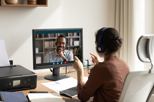 Mujer habla con colega africano usando PC y aplicación de videollamada photo