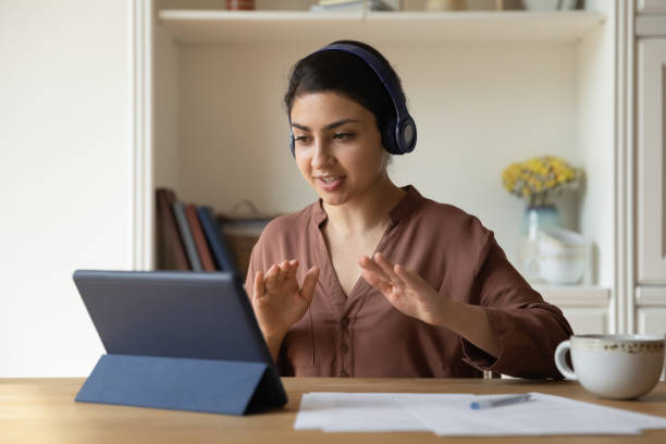 istock Student woman engaged in e-learning through videocall app on tablet 1352734373