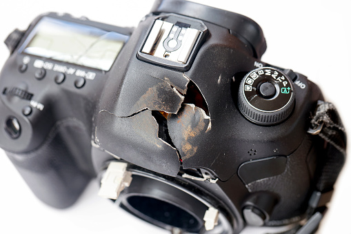 Damaged DSLR camera, elevated view, background with copy space, full frame horizontal composition