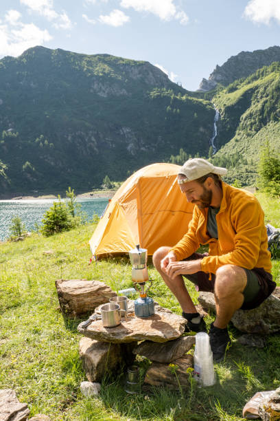istock Man camping near mountain lake, prepares coffee 1352735741