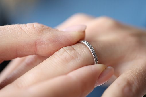 Woman hand putting silver ring on her finger closeup. Lgbt legal marriage concept