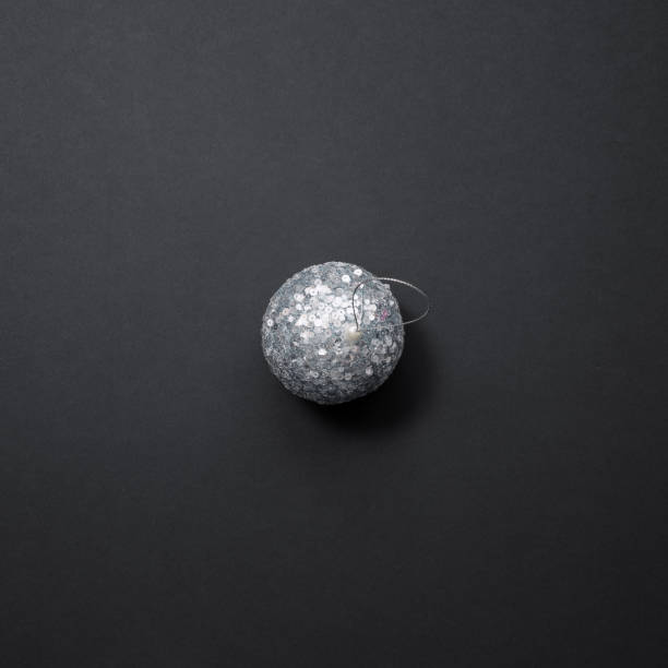 istock A shiny silver Christmas tree ball covered with sequins lies on a black background. Christmas decor 1352736981