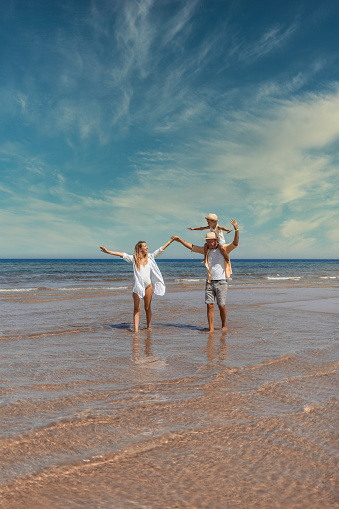 A family walks hand in hand down a tropical paradise beach