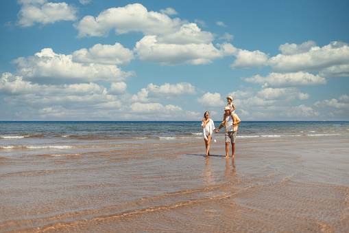 A family walks hand in hand down a tropical paradise beach