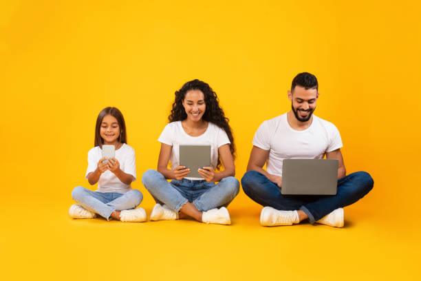 istock Middle-Eastern Family Using Gadgets, Computers And Smartphone Over Yellow Background 1352737319