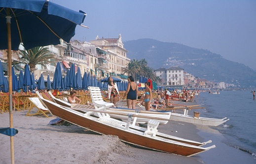 Alassio, Liguria, Italy, 1969. The beach in the Ligurian town of Alassio. Furthermore: bathers, tourists, hotels, sun loungers and rental boats.