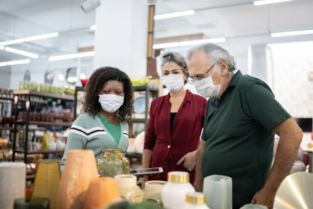 Saleswoman helping a couple at a store - using a face mask