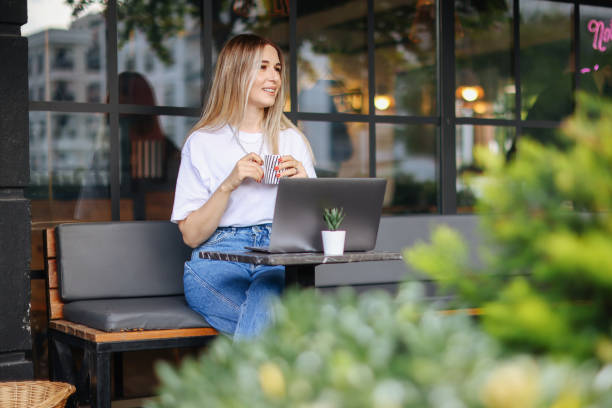 istock Relaxed Young Woman Working on Laptop in Cafe 1352744212