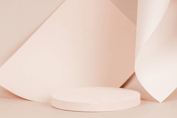 istock Abstract trendy composition with empty round podium platform for product presentation and curve shaped paper on pastel beige background. Front view 1352745131
