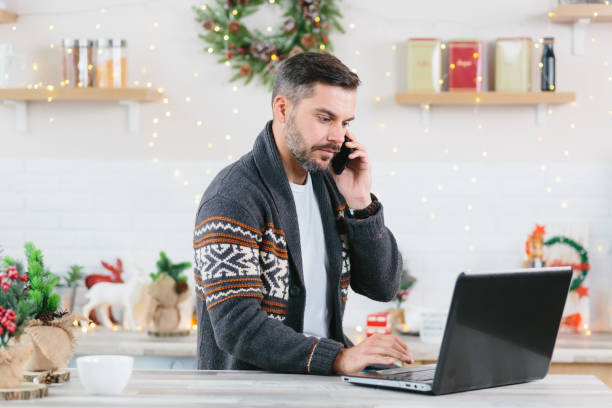 istock Serious and confident man working at home on a laptop talking on a mobile phone during the New Year and Christmas holidays 1352747307