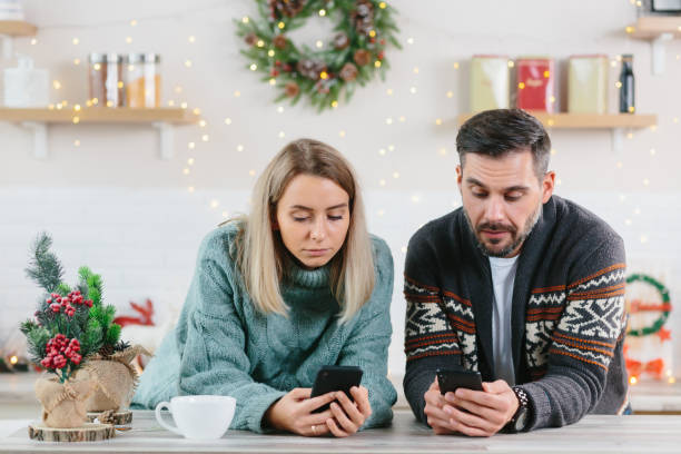 homem e mulher em casa olhando celulares passando tempo nas redes sociais, natal e ano novo - mobile phone home video camera video photograph - fotografias e filmes do acervo