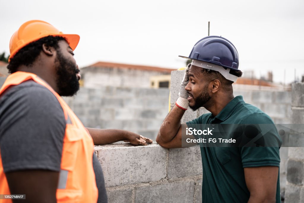 Worried coworkers talking in a construction site Construction Site Stock Photo