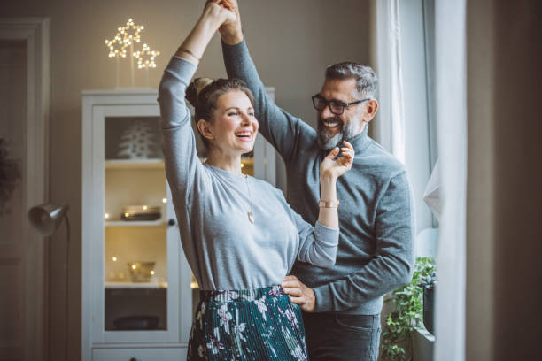 Mature couple for Christmas at home Mature couple for Christmas at home. They are standing in front of window and dancing. couple relationship stock pictures, royalty-free photos & images