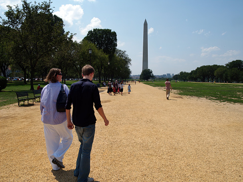 Washington D.C. USA August 6, 2010: A woman and a young man walk down the National Mall towards the Washington Monument in summer.